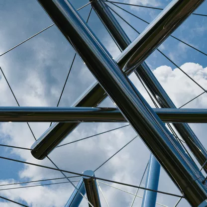 Steel sculpture against blue sky with clouds